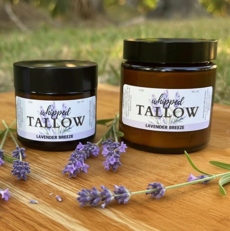 Two jars of 'whipped tallow' with lavender flowers on a wooden surface.